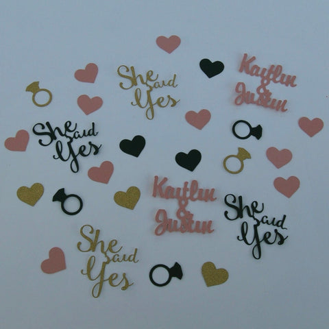 She said yes confetti with gold engagement rings, light pink hearts, navy accents, and custom couples names for engagement party table decor